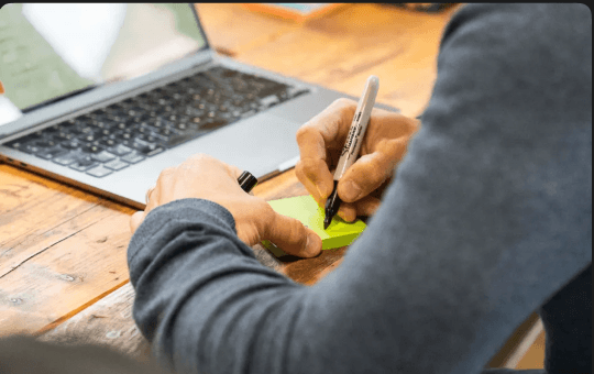 A Forge team member sketching notes beside a laptop